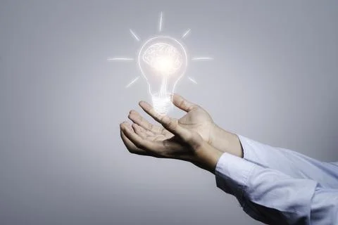 Two hands holding the drawing light bulb that is illuminating. Stock Photos