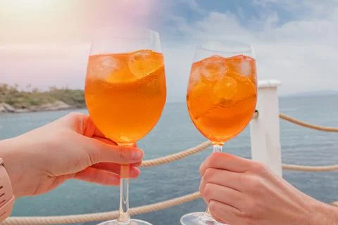 Two hands holding drinks over the sea Stock Photos