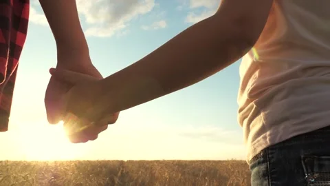Two hands holding each other against sunset, mother child holding hands sunset Stock Footage 305743828