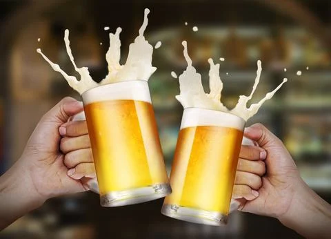 Two hands holding a glasses of light beer toasting with bubble froth splash.. Foto stock