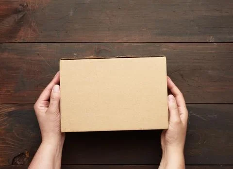 Two hands holding a rectangular cardboard box of brown kraft paper Stock Photos