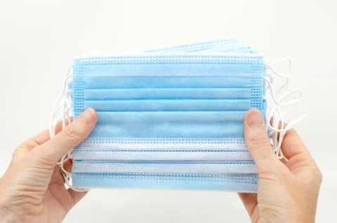 Two hands holding several disposable surgical face masks to cover the mouth a Stock Photos