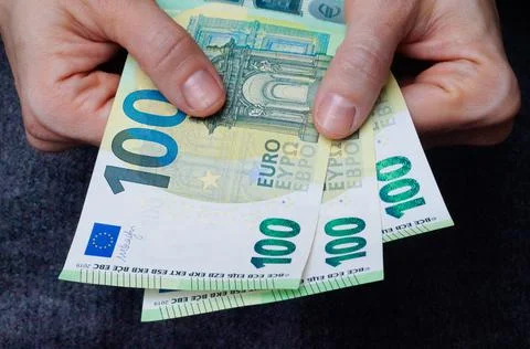 Two hands holding three one hundred euro banknotes. Close up Stock Photos
