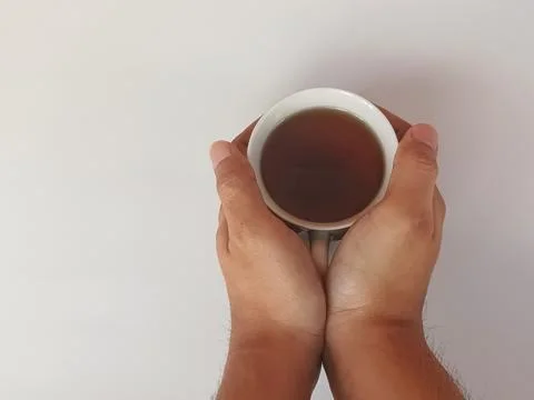 Two hands holding warm coffee cup on white background 스톡 사진