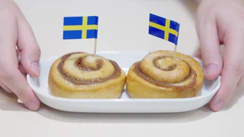 Two hands holding a white ceramic plate with two Swedish cinnamon buns, kno.. Stock Footage 333286911
