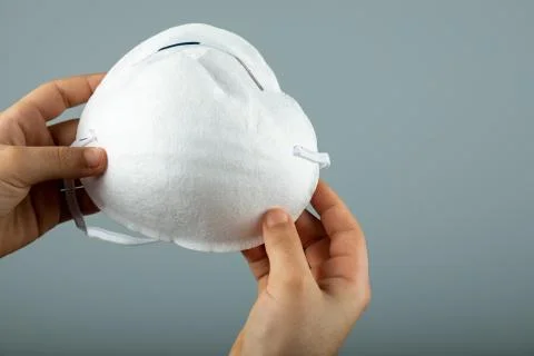 Two hands holding a white modern medical face mask Stock Photos