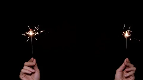 Two Hands holds and waves a sparkler on dark or black background. New year or Stock Footage 161334230