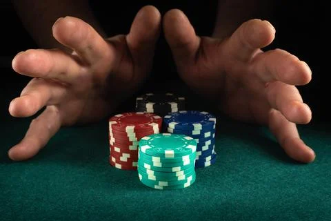 Two hands hover over a collection of poker chips in various colors stacked on Foto stock