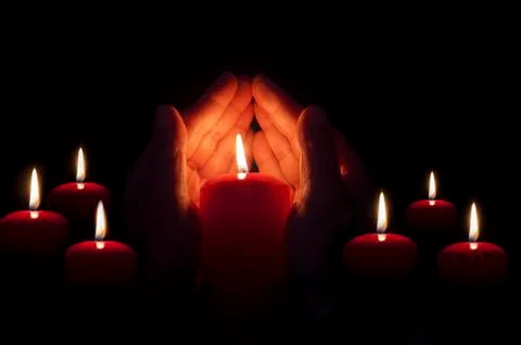 Two hands illuminated by  a candle Stock Photos