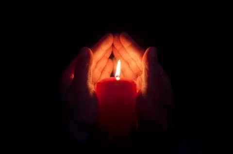 Two hands illuminated by  a candle Stock Photos