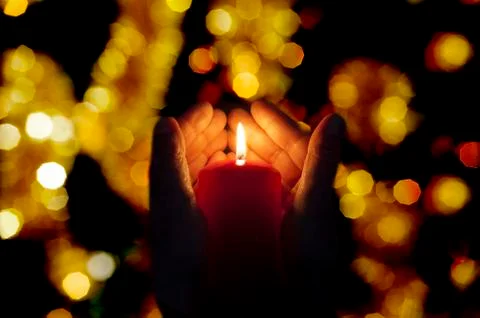 Two hands illuminated by  a candle Stock Photos