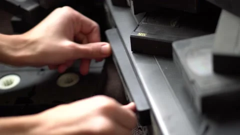 Two hands insert a video cassette into VCR Video stock 234407454