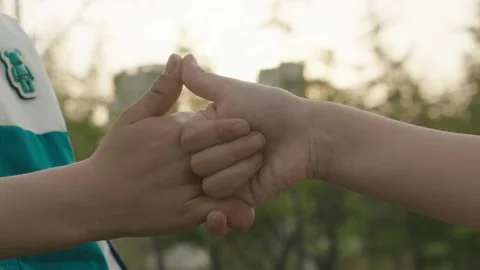 Two Hands Interlocking Thumbs in Outdoor Park Setting Stock Footage 339075199
