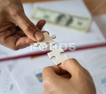 Two hands joining together two jigsaw puzzles Stock Photos