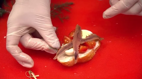 Two hands making tapas on cutting board with cheese and fish closeup Stock Footage 77025879