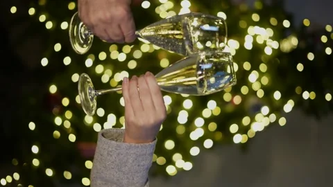 Two hands making a toast with two glasses of champagne on the golden blurred Stock Footage 165521879