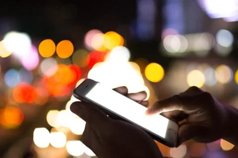 Two hands of man playing smartphone with bright white monitor Stock Photos