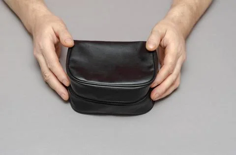 Two Hands of a middle-aged man holding a black bag against a gray background. Stock Photos
