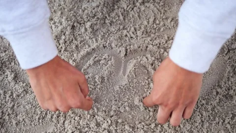 Two hands move in harmony, drawing a heart on the sand at the same time As the Vidéo 282737365