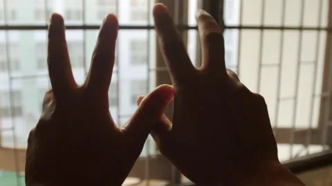 Two hands moving fingers gesturing in air against window Vidéo 336665499