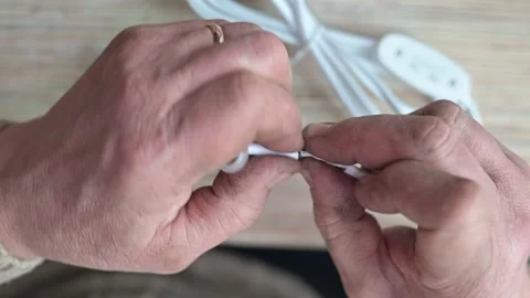Two hands neatly organize and tie white cables for storage. 스톡 동영상 337111254
