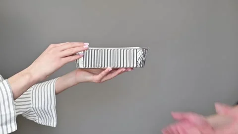 Two hands pass a rectangular container back and forth against a plain background Stock Footage 337556928