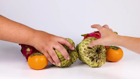 Two hands picking up custard apples from a selection of tropical fruits inc.. Stock Footage 332826738