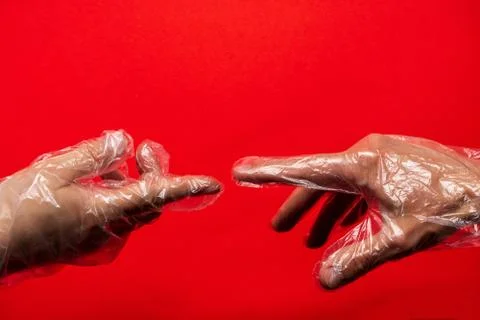 Two hands in plastic or rubber gloves on red background. The fingers are almo Stock Photos