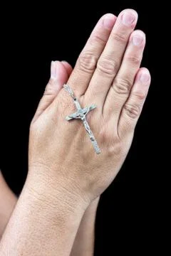 Two hands praying with a small silver crucifix Stock Photos