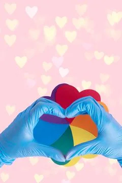 Two hands in protective blue gloves show a heart shape over an iridescent pap Stock Photos