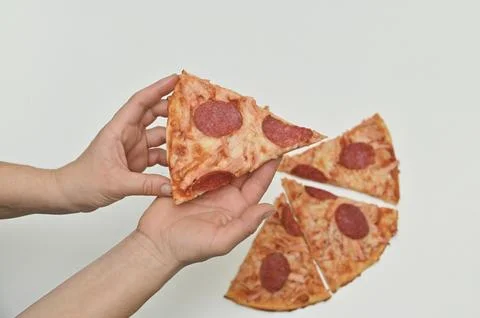 Two hands pull apart slices of a pepperoni pizza, showcasing the cheesy str.. Stock Photos