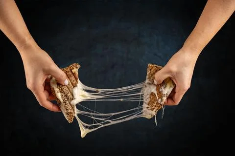 Two hands pulling apart a grilled cheese Stock Photos