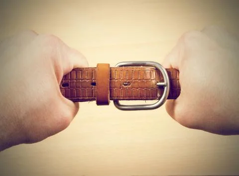 Two hands pulling a leather belt Stock Photos
