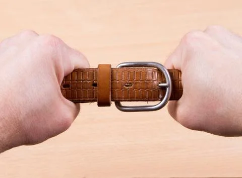 Two hands pulling a leather belt Stock Photos