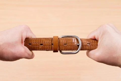 Two hands pulling a leather belt Stock Photos