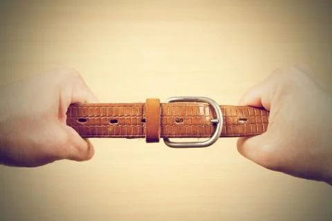 Two hands pulling a leather belt Stock Photos