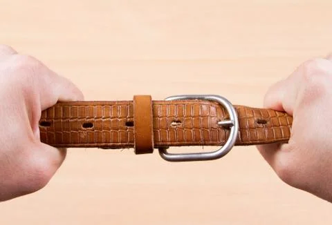 Two hands pulling a leather belt Stock Photos