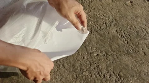 Two hands putting several white paper sheets into a plastic bag on top of a.. Stock Footage 324822226