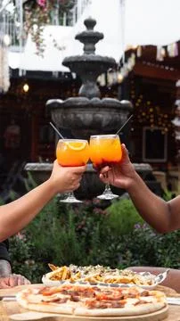 Two hands raise orange drinks in a toast Stock Photos