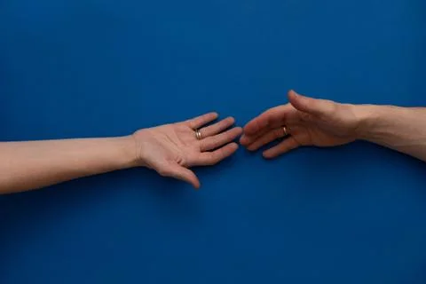 Two hands reaching to hold each other on blue background Foto stock