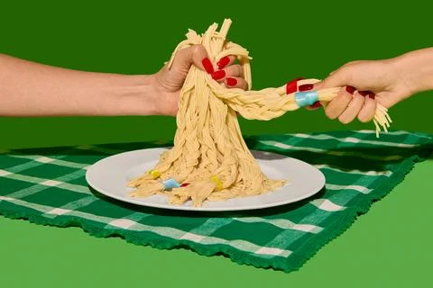 Two hands with red nails pulling braided spaghetti strands with colorful bands Stock Photos