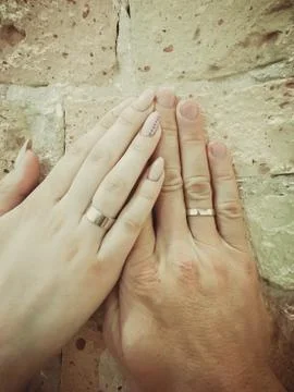 Two hands with rings on a light brick wall Stock Photos