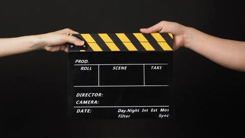 Two hands send and hold yellow clapper board or movie slate on black backgr.. Stock Photos