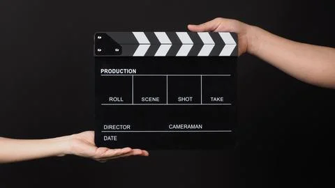 Two hands send and hold Black clapper board or movie slate on black backgroun Stock Photos