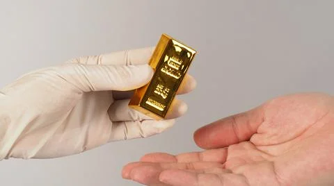 Two hands send and recive gold bar on white background. One Hand wear latex g Foto stock