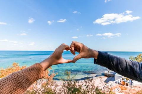 Two hands in the shape of a heart on the background of the sea. Honeymoon. Stock Photos