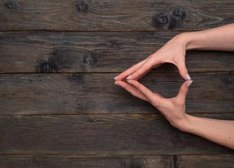 Two hands shape a triangular figure with fingers placed carefully on wooden.. Stock Photos