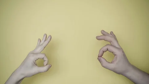 Two hands show signs: Ok, moving.Yellow background. Close up Stock-Footage 128985973
