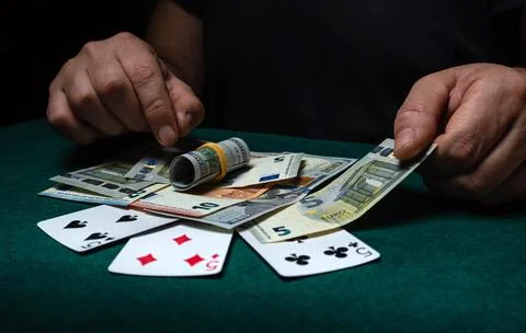 Two hands sort cash and poker cards on a green table at night in a gaming r.. Stock Photos