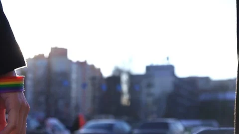 Two hands stretch to each other with LGBT bracelets against the backdrop of the Video stock 87595545